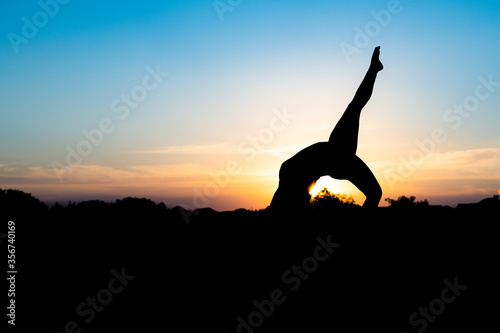 Fototapeta Naklejka Na Ścianę i Meble -  silhouette of woman doing yoga in the sunset