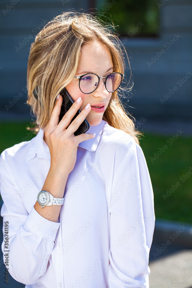 Young assistant in a white blouse phoning on the street Young assistant in a white blouse phoning on the street