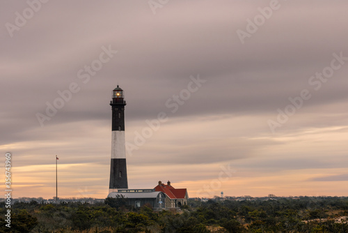 Lighthouse beacon shining as storm clouds streak across the sky. Fire Island New York