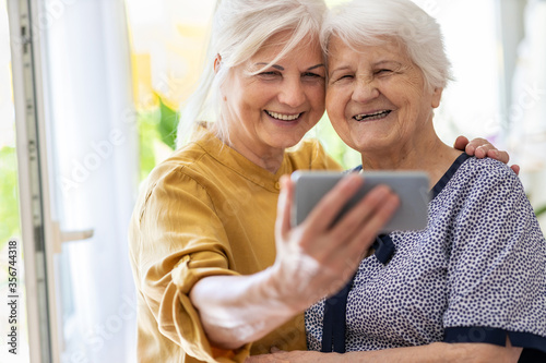 Senior woman and her adult daughter using smartphone together
