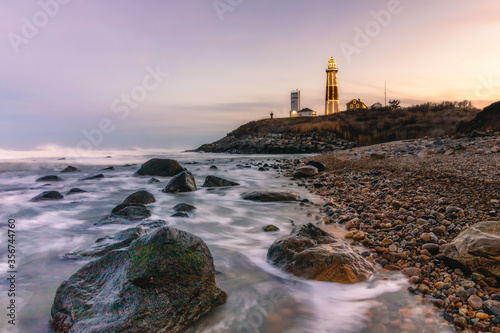 Lighthouse lit up with Christmas lights in a winter seascape along a rocky coast. Montauk State Park, New York. 