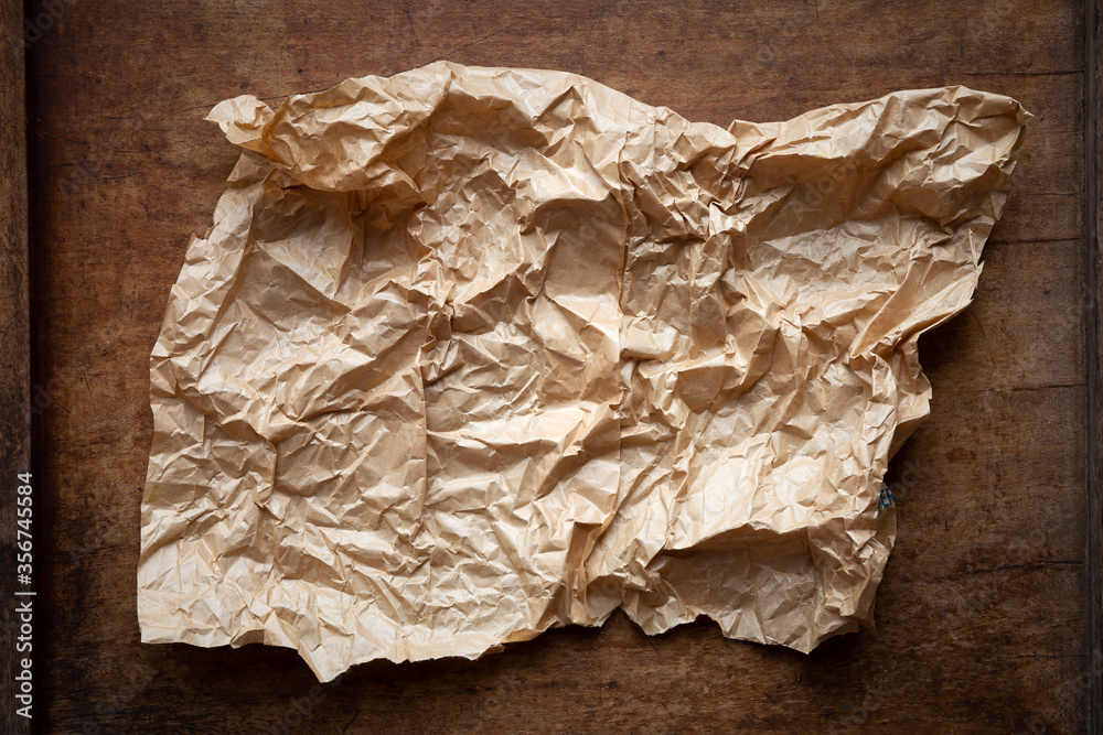 Obraz premium Creased sheet of brown paper on a dark rustic wooden background