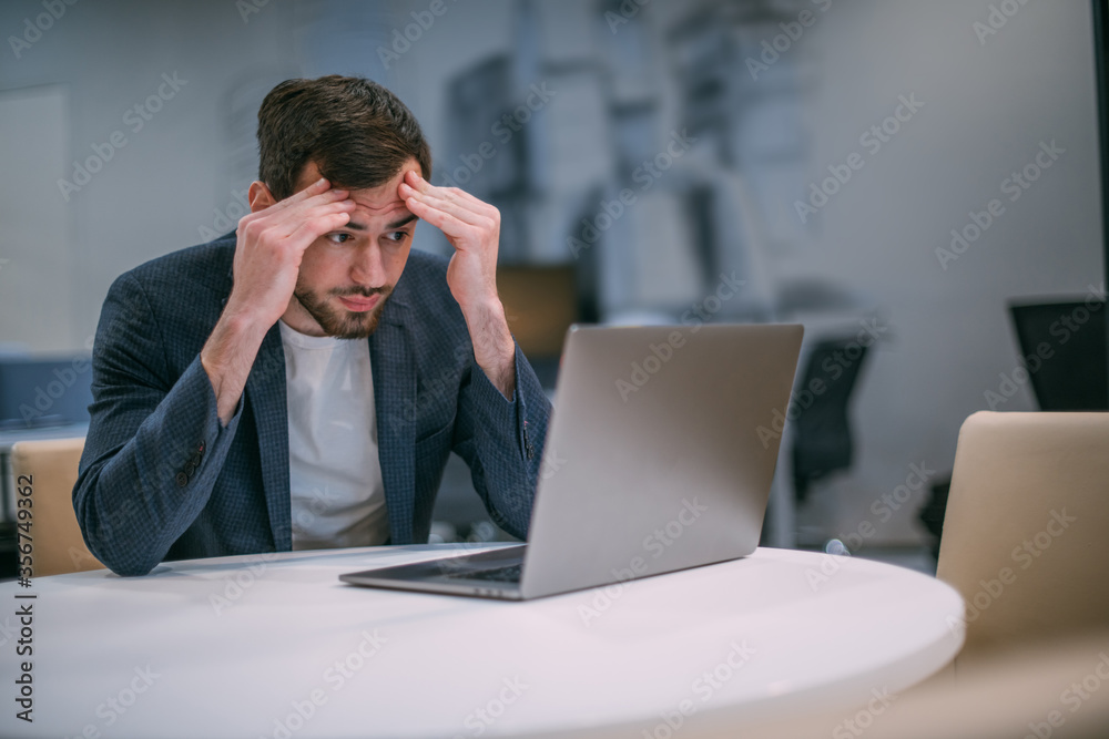 Portrait of a sad young businessman at a working laptop. Portrait of a sad young businessman at a working laptop.