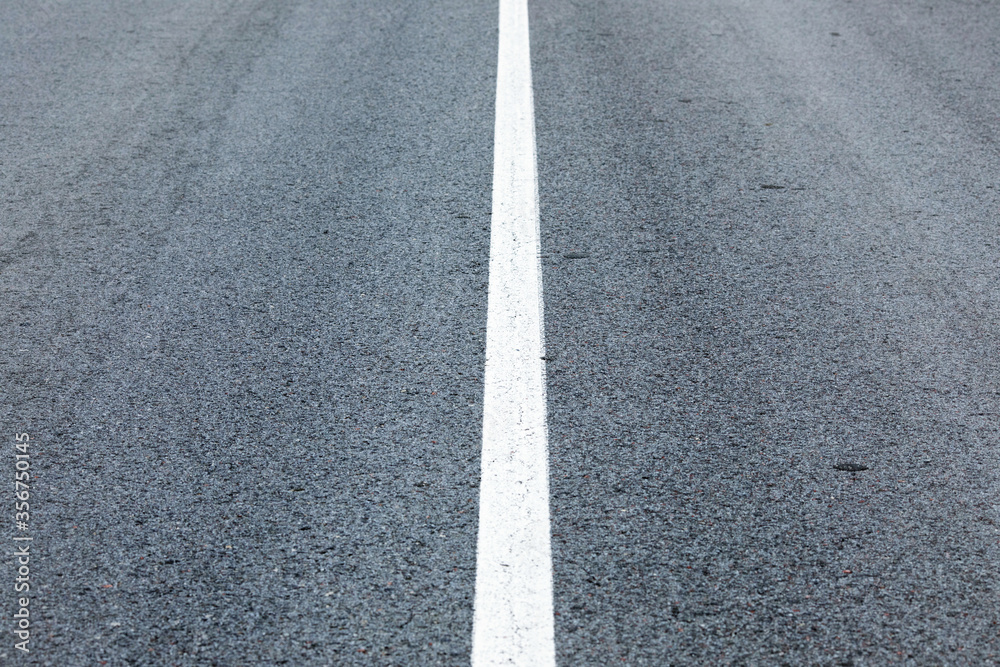 long lonely old asphalt road horizontal background with a white solid stripe