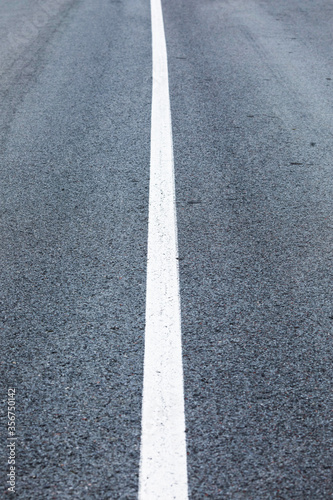 long lonely old asphalt road vertical background with a white solid stripe