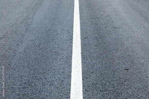long lonely old asphalt road horizontal background with a white solid stripe