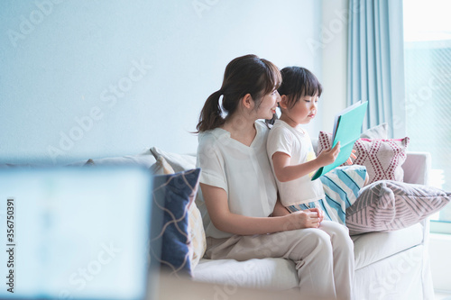 ソファに座って絵本を読む親子 photo