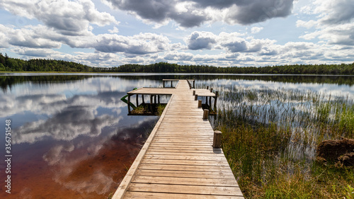 Wallpaper Mural Landscape with a swamp lake and with a wooden footbridge. Beautiful clouds and the surrounding forest were reflected in dark water. Latvia. Lake Ratnieku Torontodigital.ca