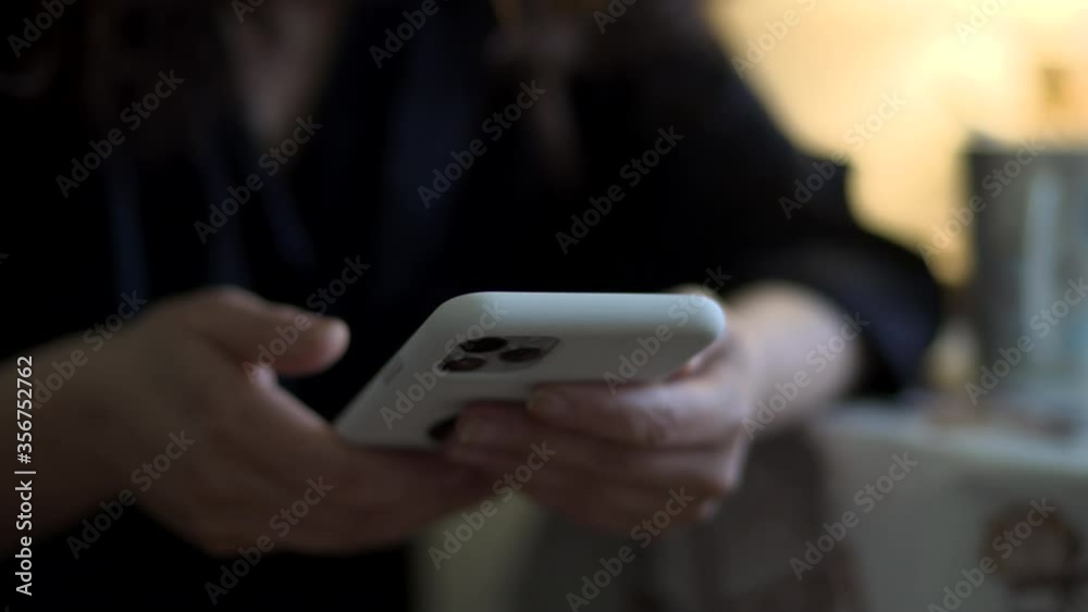 Woman holding mobile phone while sitting at table in the kitchen, close-up female hands with phone. Woman holding mobile phone while sitting at table in the kitchen, close-up female hands with phone.