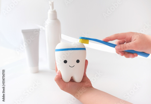 little girl's hands cleaning toy tooth with toothbrush. oral hygiene concept. cleaning teeth and dental care importance. morning routine presentation