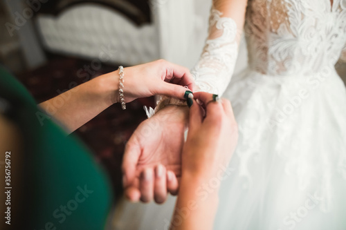 Hands of bridesmaids on bridal dress. Happy marriage and bride at wedding day concept
