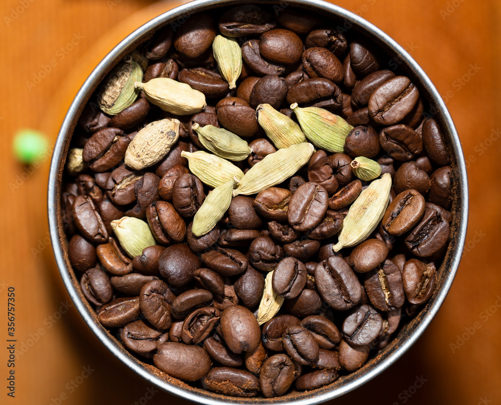 Black coffee beans and Green cardamom pods. Grinding raw materials for a drink in a coffee grinder. Black coffee beans and Green cardamom pods. Grinding raw materials for a drink in a coffee grinder.