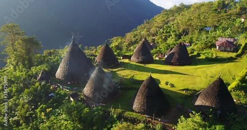 Wae Rebo traditional village on Flores island, an Unesco heritage site, down-looking aerial sunny view over the woody houses with villagers walking around, must-see destination in Indonesia and Asia photo