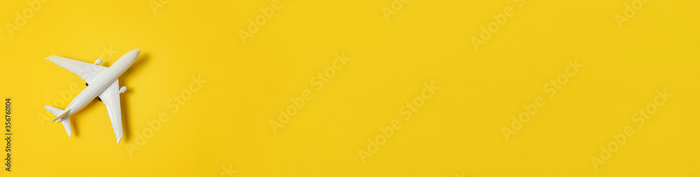 Simply minimal design miniature toy model plane on yellow colorful background. Travel by plane vacation summer weekend sea adventure trip journey ticket concept. Flat lay top view copy space banner