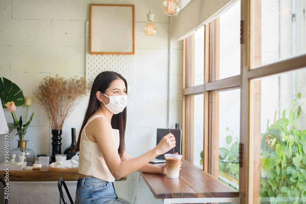 Beautiful young Woman with face mask is sitting in coffee shop Beautiful young Woman with face mask is sitting in coffee shop