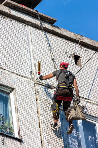 An industrial climber works. industrial climber makes repair of the walls of a multi-storey building