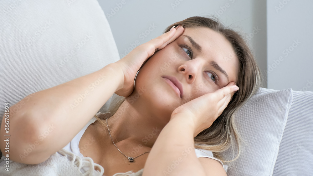 Portrait of woman suffering from headache or migraine lying on pillow Portrait of woman suffering from headache or migraine lying on pillow