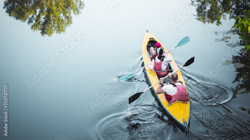 Family kayaking together in river.Tourists kayakers woman,man and child touring canoeing in a lake on a summer day.Back view.Summer family travel vacation concept. Active rest, water sports