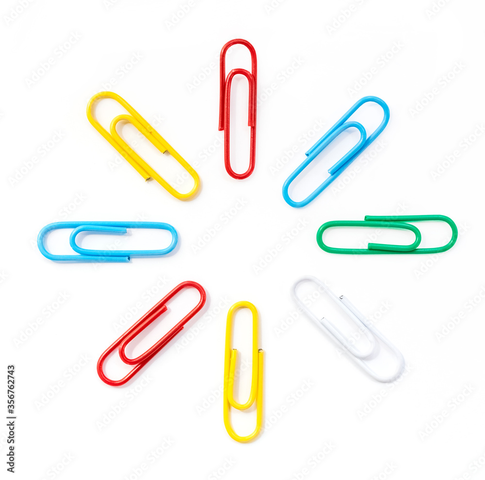 Colored paper clips arranged in a circle in the shape of the sun, close-up. White background Colored paper clips arranged in a circle in the shape of the sun, close-up. White background