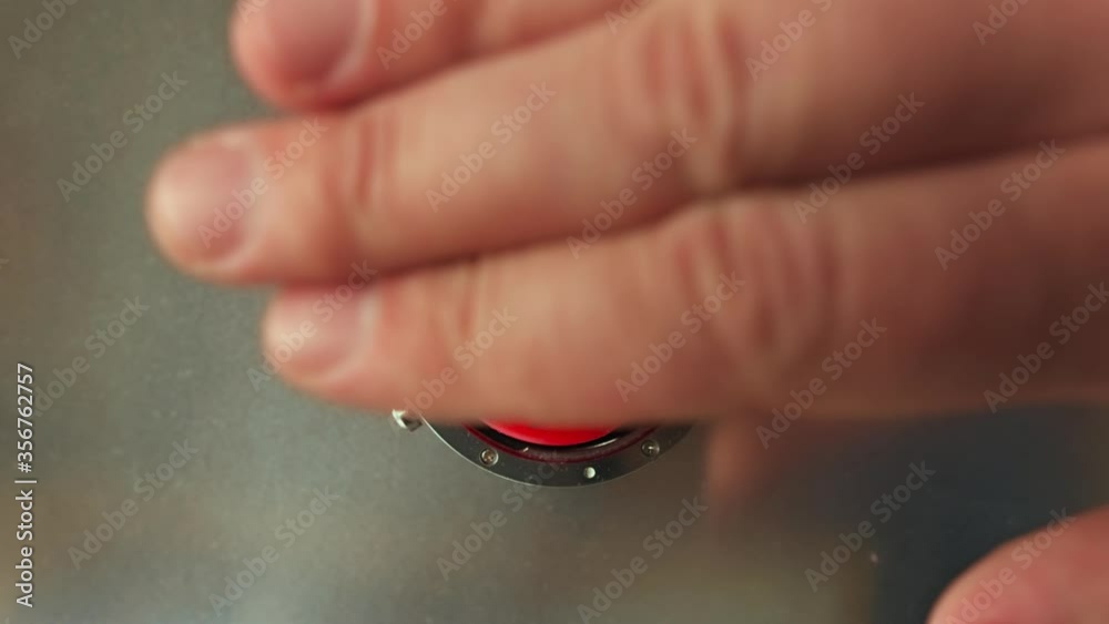 Hand presses the big red button 