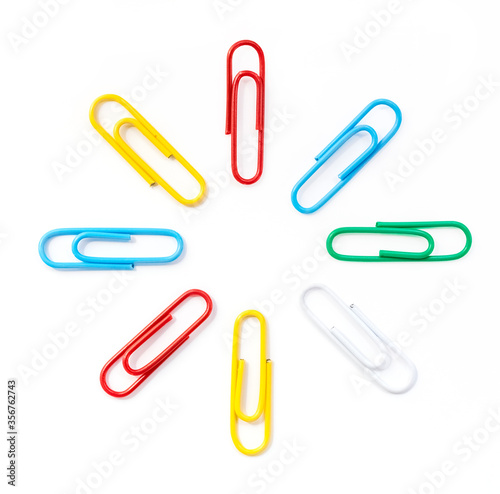 Colored paper clips arranged in a circle in the shape of the sun, close-up. White background