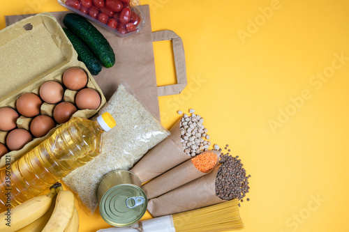 Food donation on a yellow bright background, copy space. Contactless delivery food. Essential food in the corner, volunteering and self-isolation help. Top view