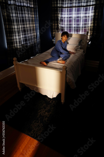 фотографія Little boy awakened by scary light and noise from closet