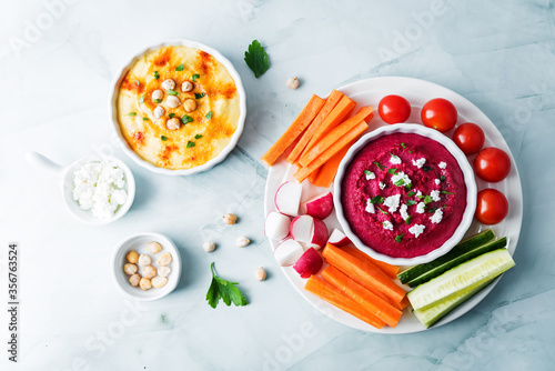 Set of classic hummus and beet hummus appetizers with carrot, radish, tomato and cucumber