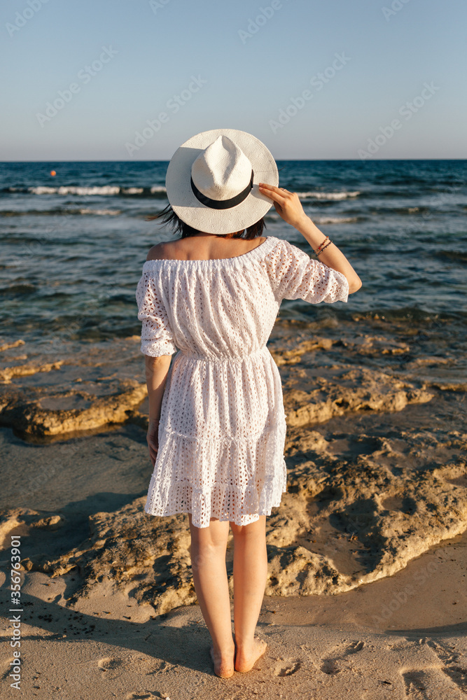 girl holds hat with hands and looks at the sea. High quality photo