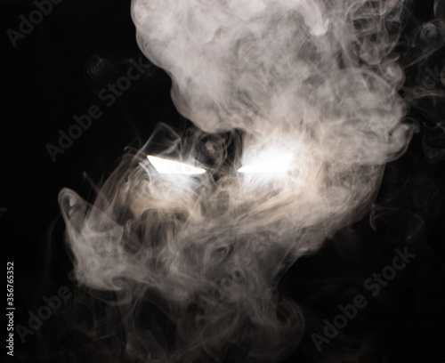 Ominous luminous eyes looking out of the darkness illuminate the swirling smoke with rays of white light