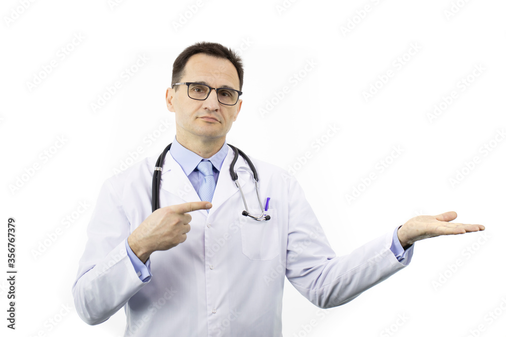 Handsome smart doctor in medical coat and stethoscope points with finger to empty open palm holding ads product isolated on white background. Health, healthcare, insurance and medicine clinic concept Handsome smart doctor in medical coat and stethoscope points with finger to empty open palm holding ads product isolated on white background. Health, healthcare, insurance and medicine clinic concept