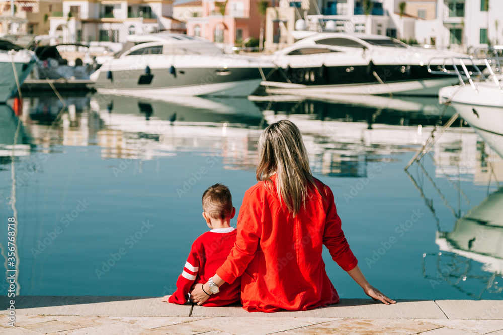 mom and son are sitting in the marina back view. High quality photo