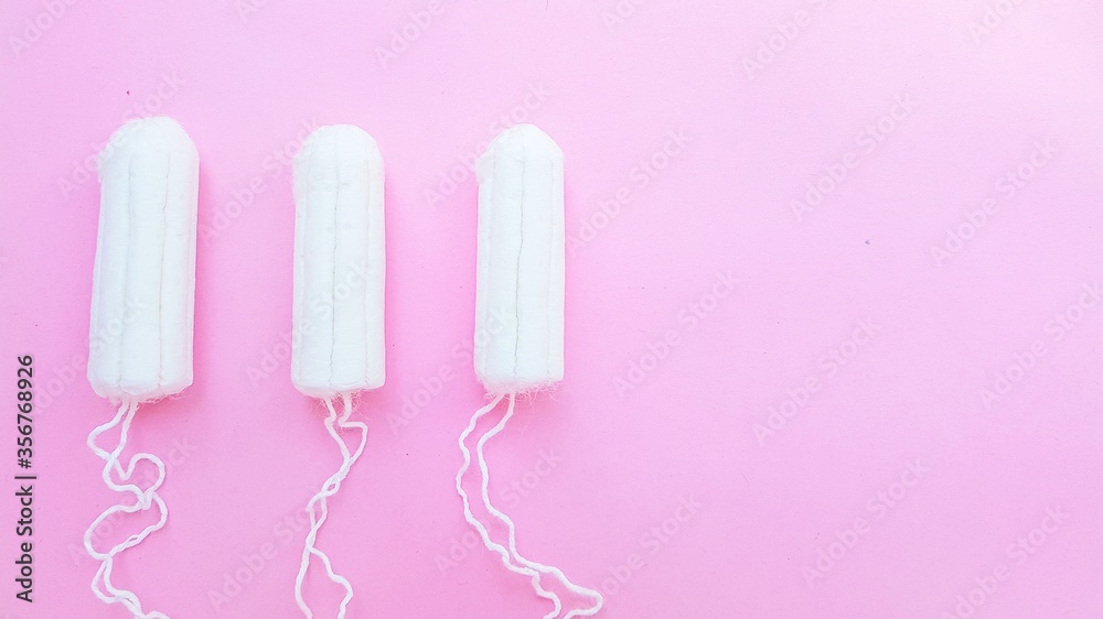 Women's hygiene intimate accessories. A clean white tampon on a pink background. Menstrual cycle. Space for text.
