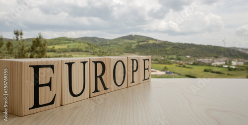 The word europe from wooden cubes. Cloudy sky and mountains in the background.