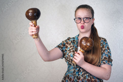 Teen girl holding maracas in her hands. Learning to play musical instruments. A blue-eyed girl  with long hair dancing with maracas. Beautiful charming young girl photo
