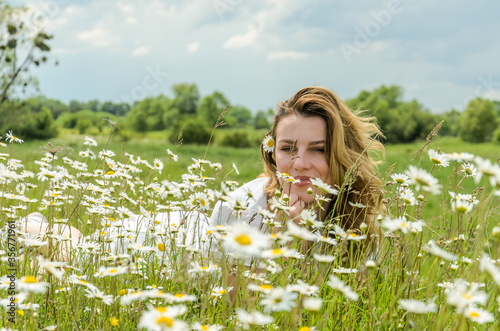 Young charming girl in a camomile field 