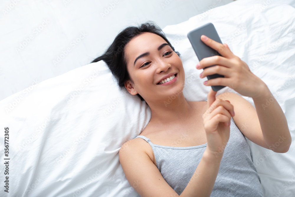 Cheerful young woman using cell phone for pleasure indoors Cheerful young woman using cell phone for pleasure indoors