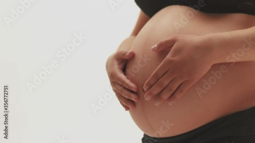 Wallpaper Mural A pregnant woman strokes bare stomach on a white background. Girl in underwear stroking a pregnant belly with two hands, on a white background Torontodigital.ca