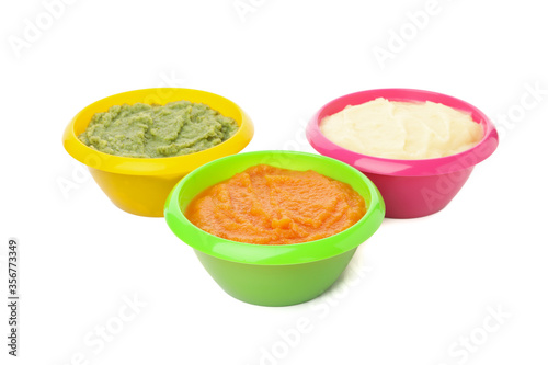 Bowls with healthy baby food isolated on white background