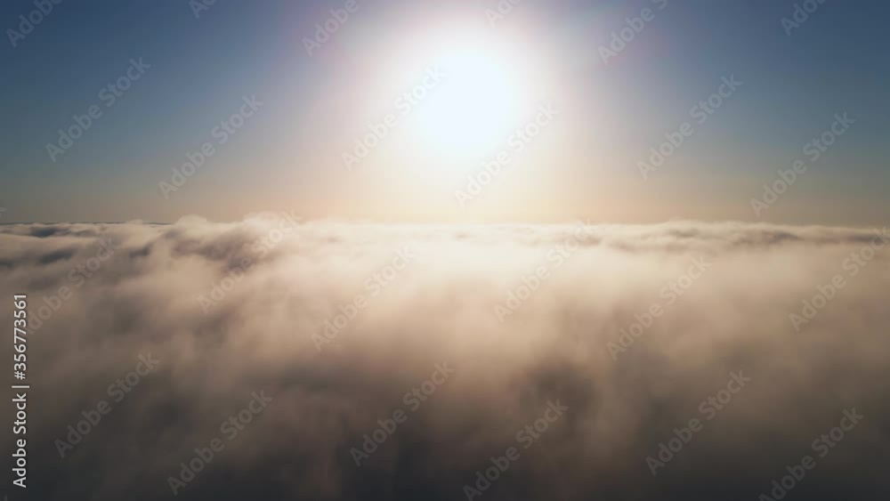 Moving white clouds blue sky scenic aerial view sunrise. Drone flies high back in blue sky through fluffy clouds in morning at bright sun summer. Sun is hidden behind clouds at fog. Relax. Nature Moving white clouds blue sky scenic aerial view sunrise. Drone flies high back in blue sky through fluffy clouds in morning at bright sun summer. Sun is hidden behind clouds at fog. Relax. Nature