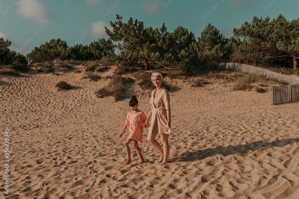 mother and daughter walking on the sand