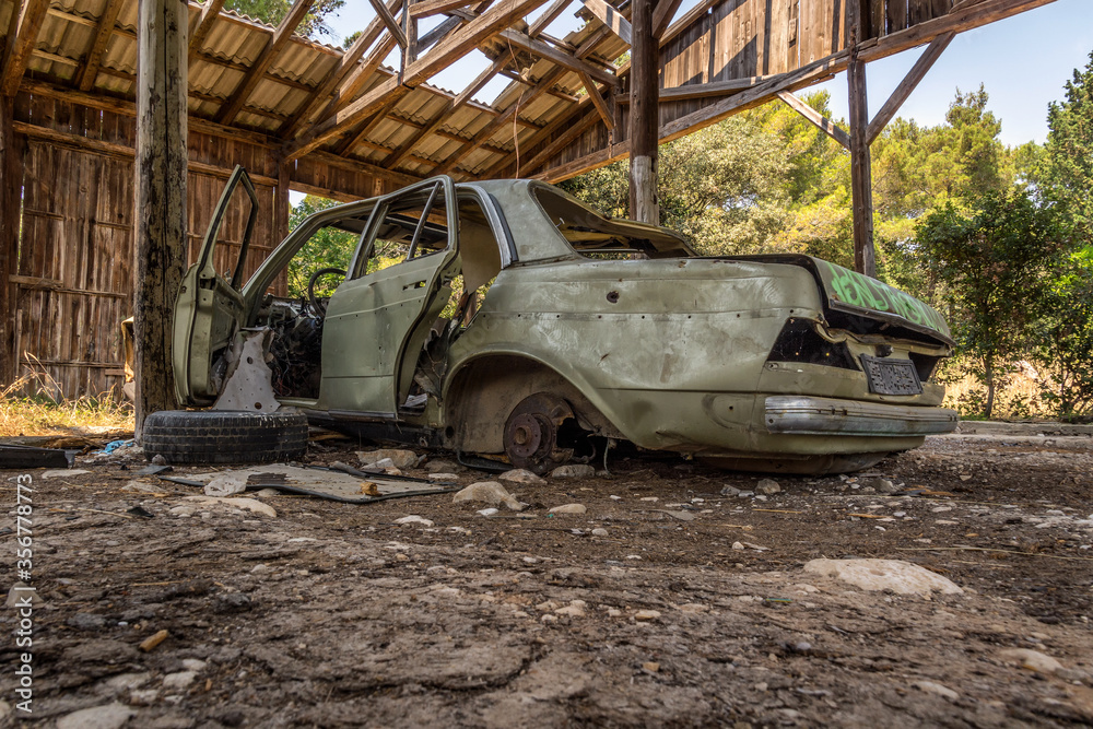 Abandoned green car in old ruined garage. Low angle view. Long period decay. Nature taking over man made objects