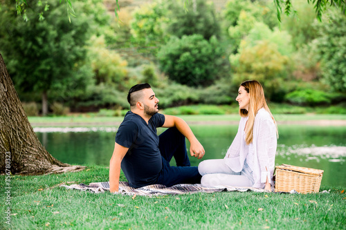 Young woman and man spending their time at the park  having a picnic.
