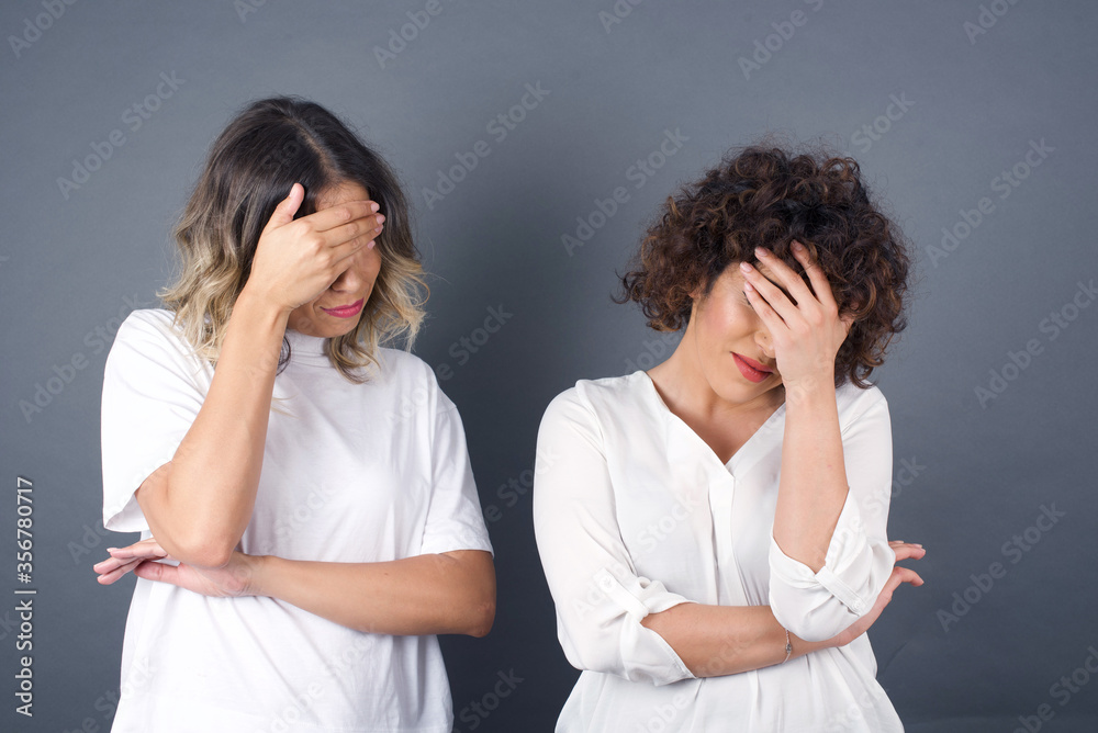 Indoor portrait of beautiful woman with stylish haircut, wearing casual clothes, making facepalm gesture while smiling, standing over gray background amazed with stupid situation. Indoor portrait of beautiful woman with stylish haircut, wearing casual clothes, making facepalm gesture while smiling, standing over gray background amazed with stupid situation.
