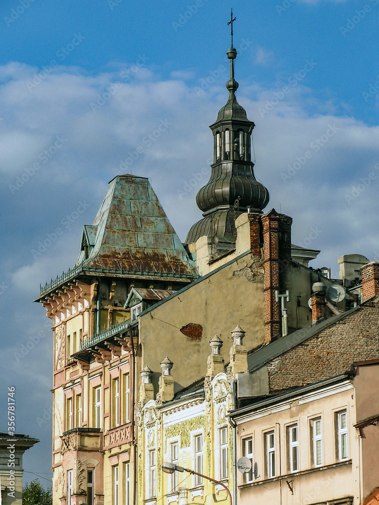 Fototapeta premium Rooftops of old houses and a church tower against the blue sky, Bielsko-Biała, Poland