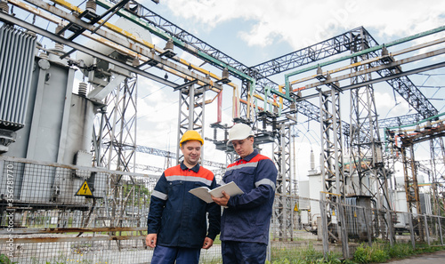 Two specialist electrical substation engineers inspect modern high-voltage equipment. Energy. Industry