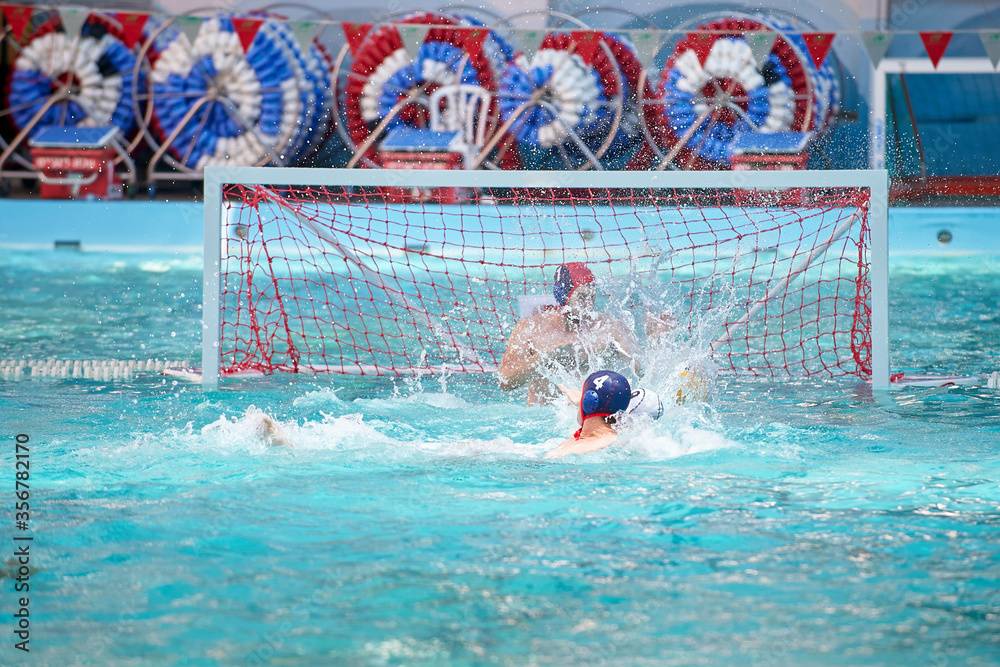 Water polo player in a swimming pool scoring goal splashing water