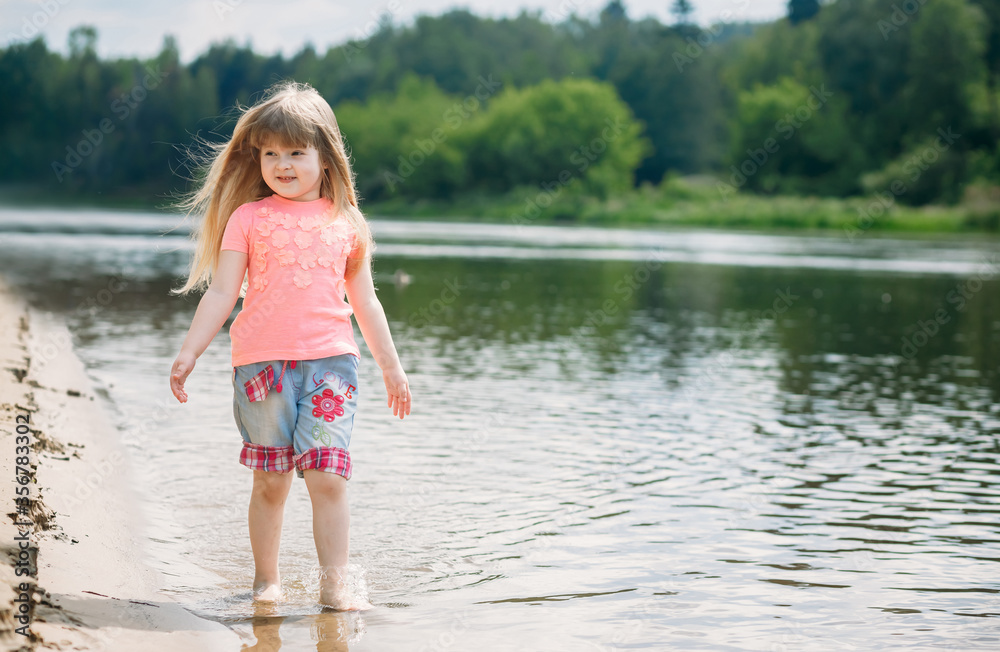 Little happy girl walks along the river
Little happy girl walks along the river