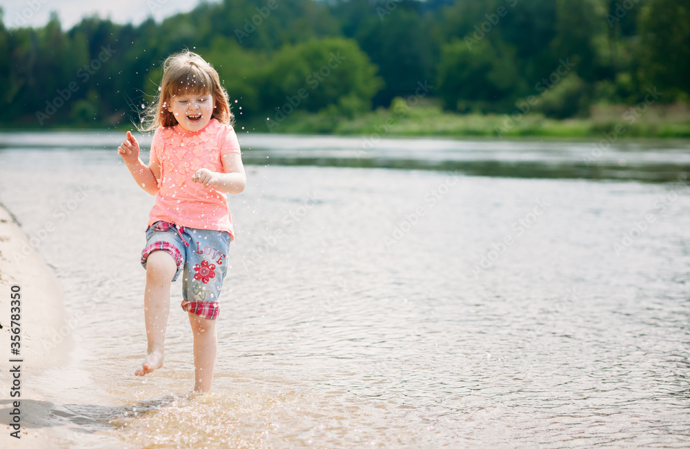Beautiful positive child running on the water, little girl with long developing hair have fun Beautiful positive child running on the water, little girl with long developing hair have fun