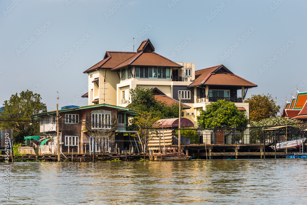 Houses on the Chao Phraya Riverside at Sunny Day in Bangkok, Thailand Houses on the Chao Phraya Riverside at Sunny Day in Bangkok, Thailand